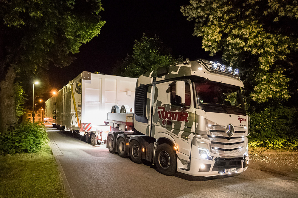 Schwertransport eines großen Industrieanlagenmoduls auf einem Spezialauflieger bei Nacht