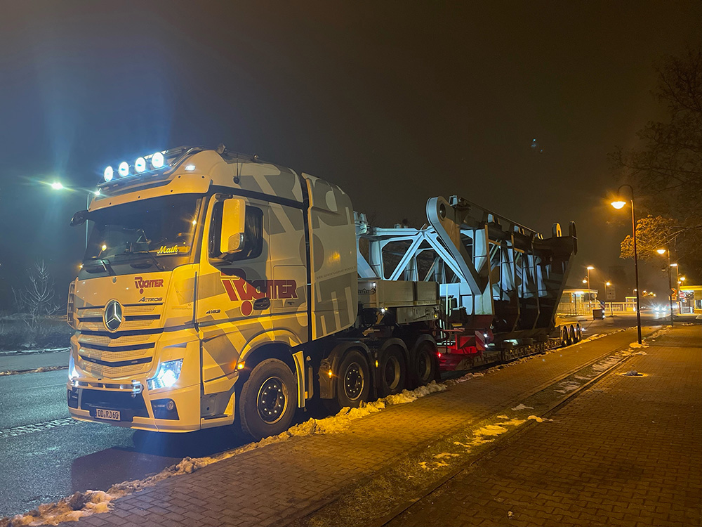 Schwertransport eines großen Stahlbauteils auf einem Spezialauflieger bei Nacht
