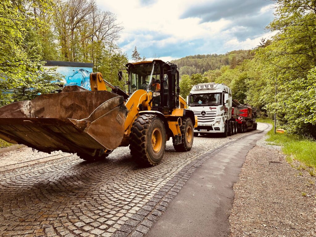 Radlader vor einem Tieflader bei der Anlieferung auf einer Baustelle