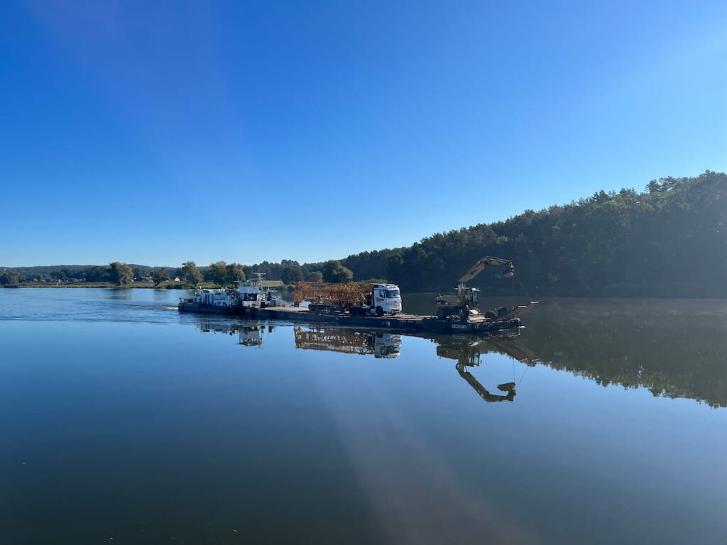 Baumaschinentransport eines Baggers auf einem Arbeitsponton über den Wasserweg