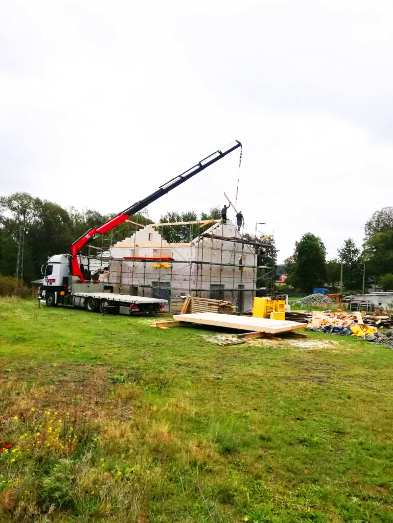 Ladekran beim Versetzen eines Holzbalkens auf einer Baustelle