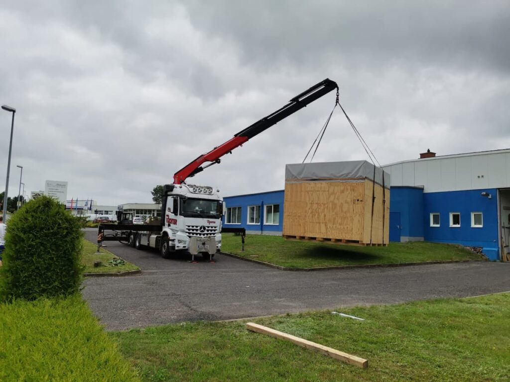 Maschinentransport einer großen Maschinenkiste mit Lkw-Ladekran
